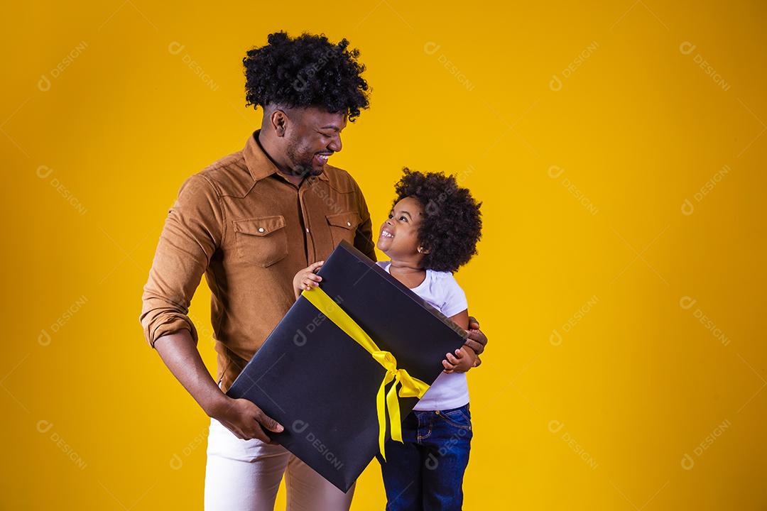 Feliz dia dos pais. Afro pai e filha em fundo amarelo segurando um presente com um laço