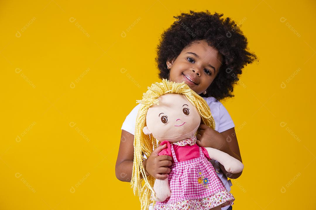Menina afro segurando uma boneca de pano