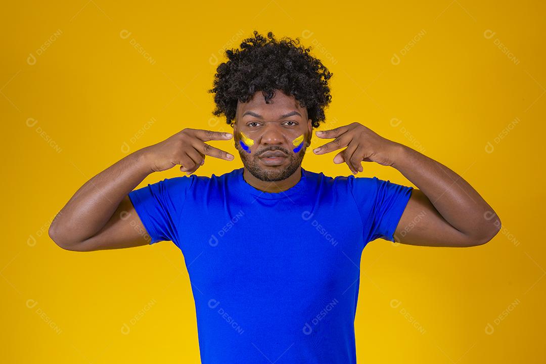 torcedor brasileiro. Fã brasileiro comemorando no futebol ou partida de futebol em fundo amarelo. Cores do Brasil.