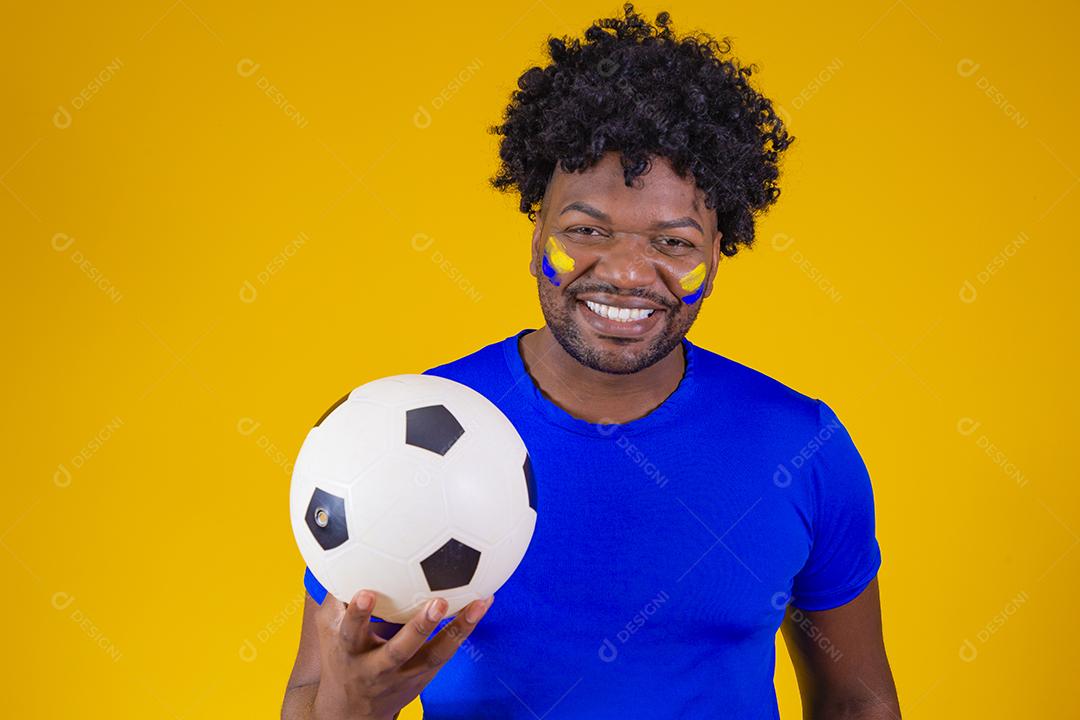 homem afro brasileiro bonito. Fã brasileira. Copa do Mundo 2022, mão no peito cantando o hino nacional