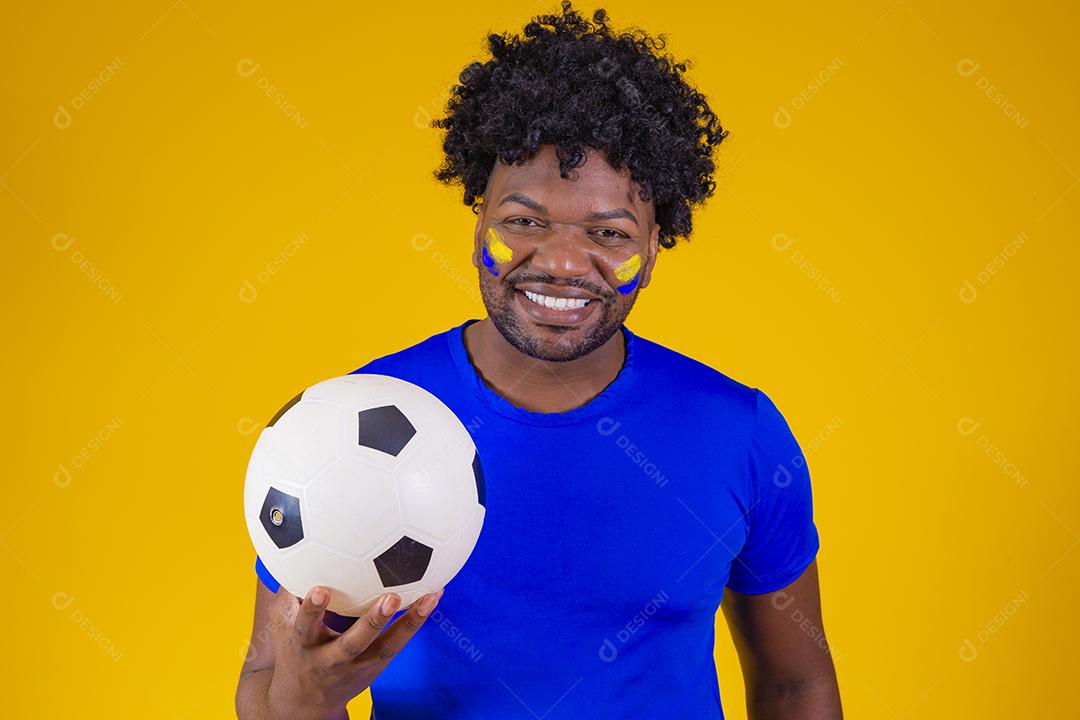 homem afro brasileiro bonito. Fã brasileira. Copa do Mundo 2022, mão no peito cantando o hino nacional