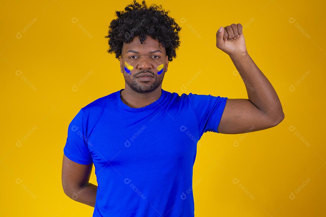homem afro com punho cerrado com sinal de militância vestido com roupas brasileiras