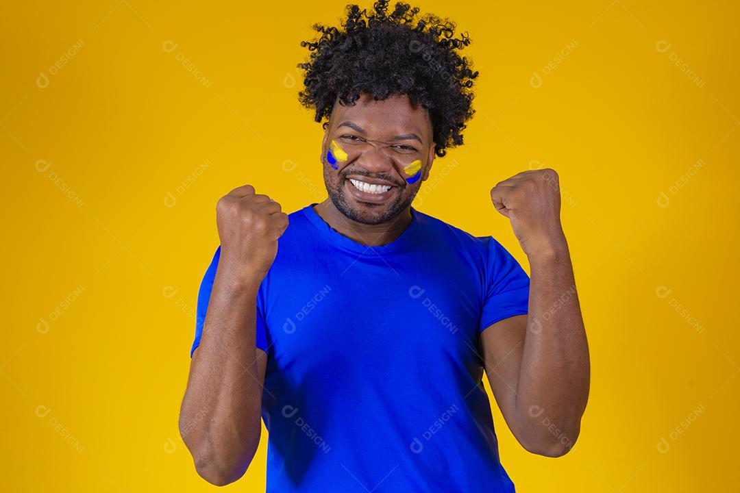 homem afro brasileiro bonito. Fã brasileira. Copa do Mundo 2022, mão no peito cantando o hino nacional