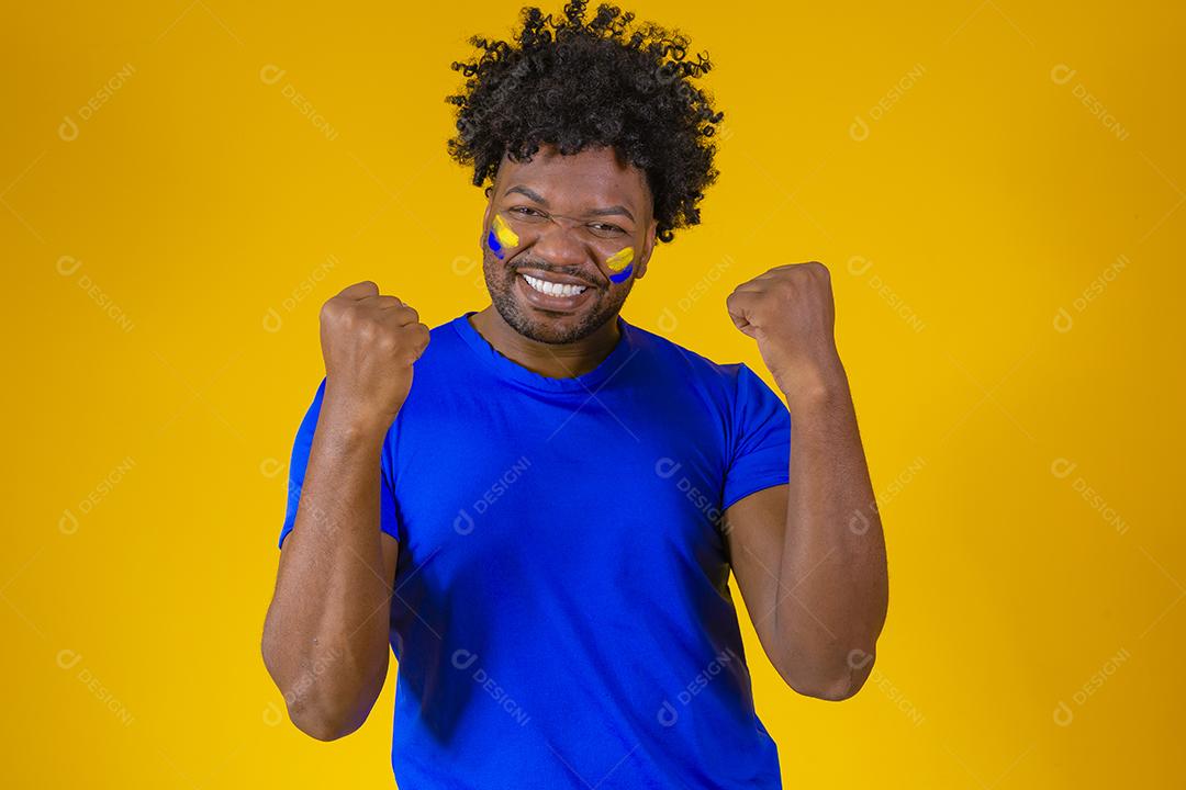 homem afro brasileiro bonito. Fã brasileira. Copa do Mundo 2022, mão no peito cantando o hino nacional