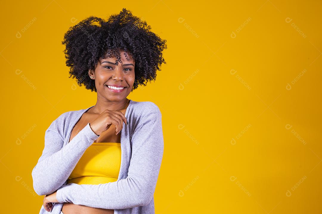 Linda mulher afro-americana olhando para a câmera. Retrato de jovem alegre com penteado afro