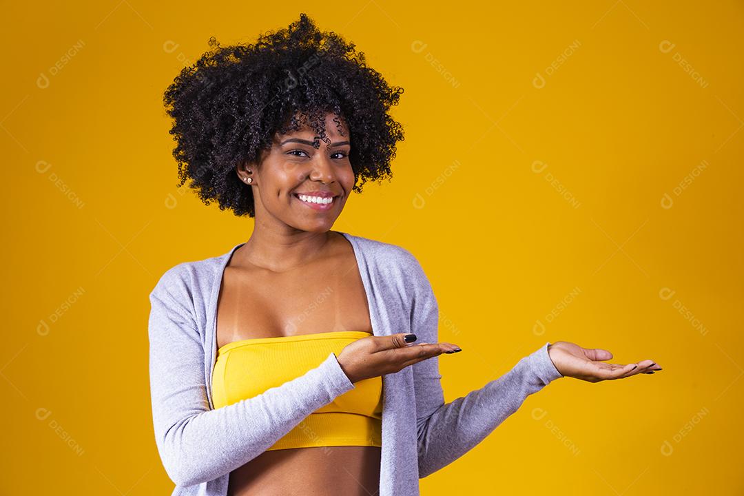 Linda mulher afro-americana olhando para a câmera. Retrato de jovem alegre com penteado afro