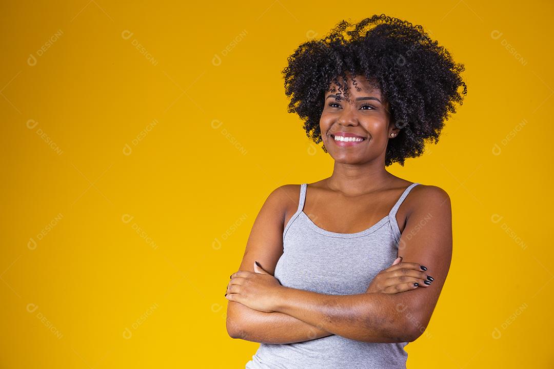 pessoas, etnia e conceito de retrato - mulher sorridente feliz na camisa com os braços cruzados sobre fundo amarelo