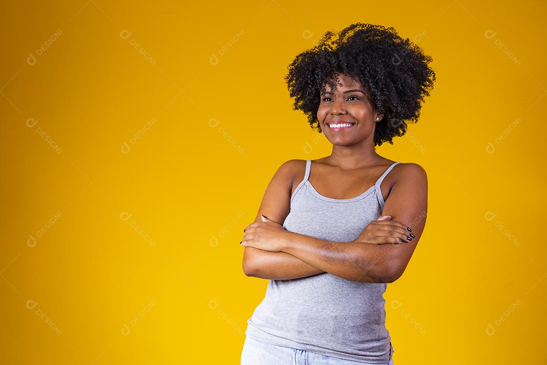 pessoas, etnia e conceito de retrato - mulher sorridente feliz na camisa com os braços cruzados sobre fundo amarelo