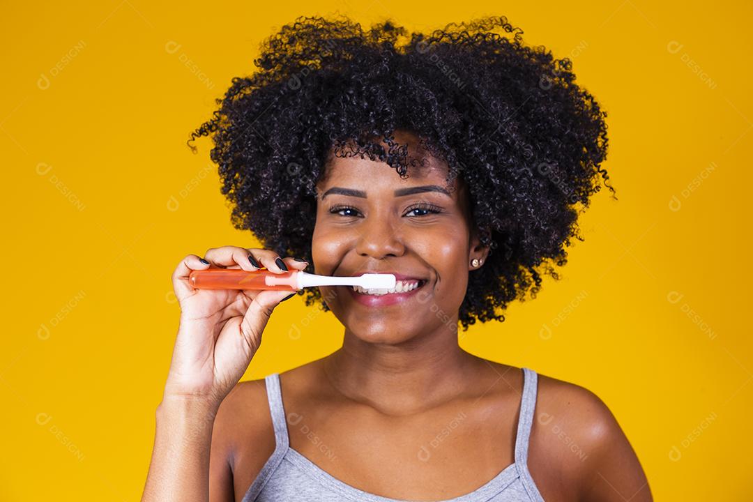 Jovem afro escovando os dentes com uma escova de dentes