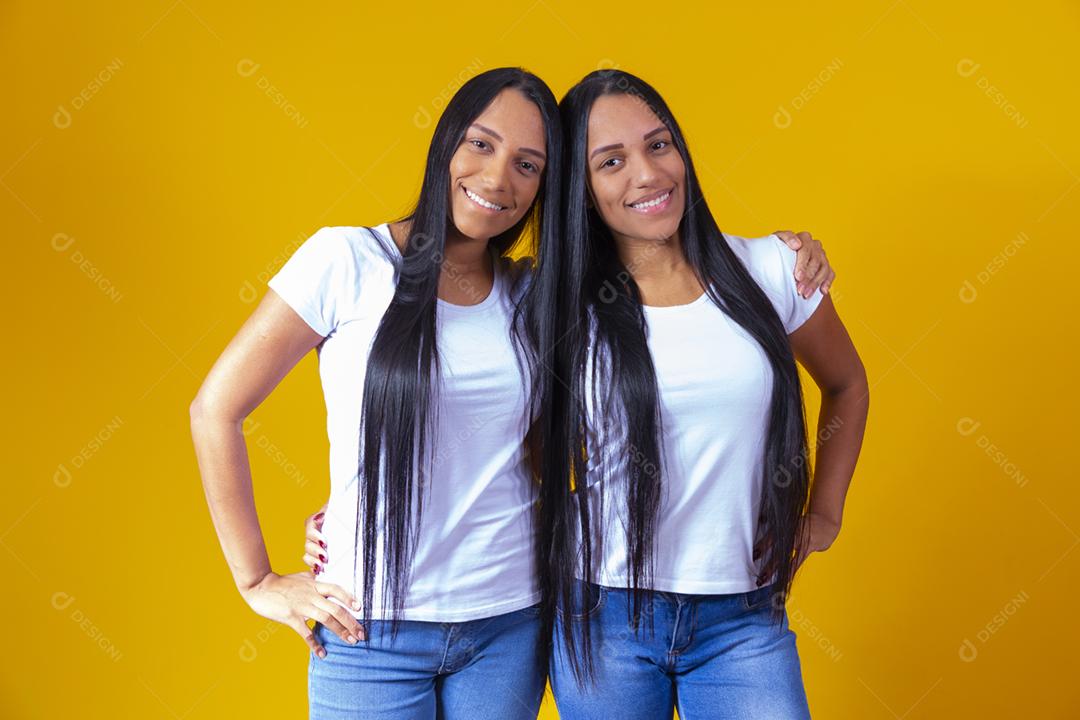 irmãs gêmeas fofas abraçando olhando para a câmera sorrindo