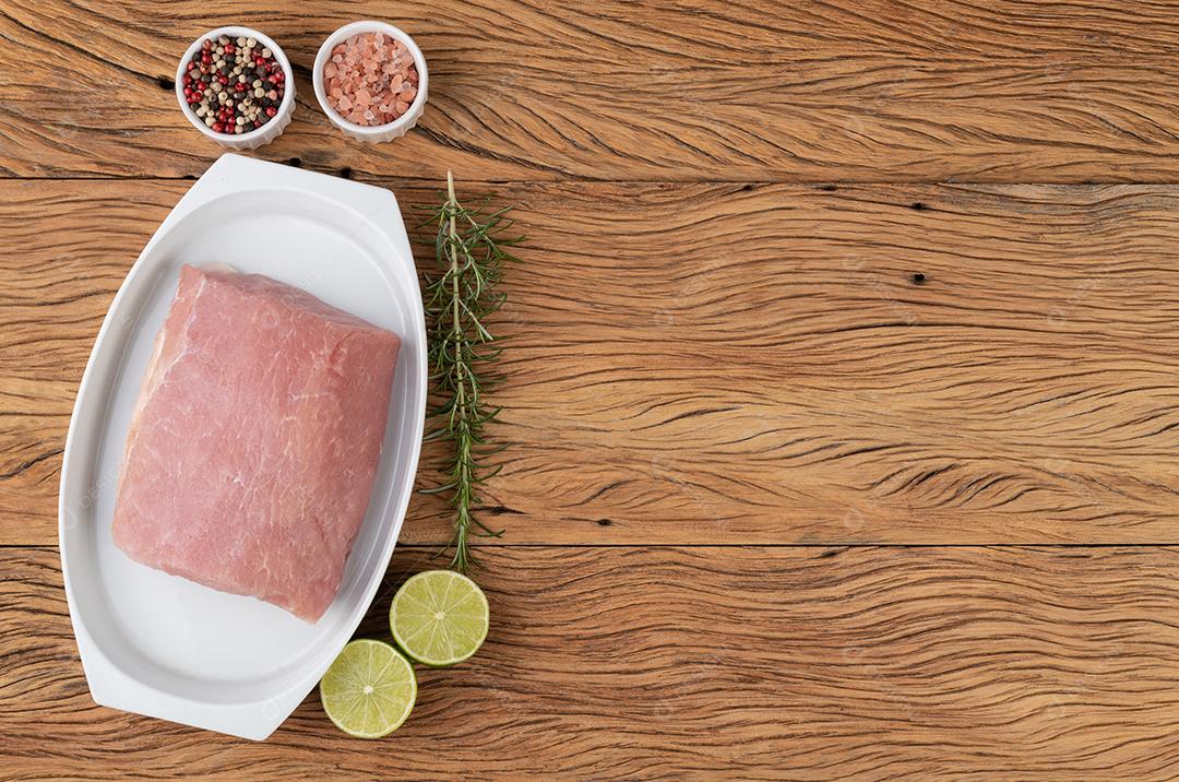 Carne de lombo de porco crua sobre chapa branca com temperos