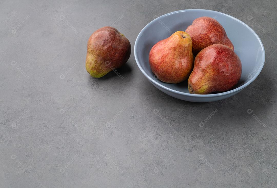 Peras vermelhas em uma tigela sobre fundo de pedra