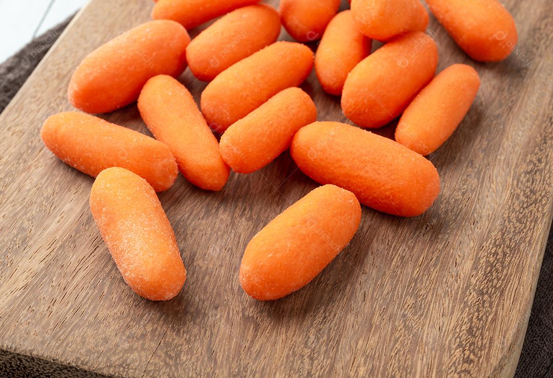 Um grupo de cenouras bebê sobre uma placa de madeira.