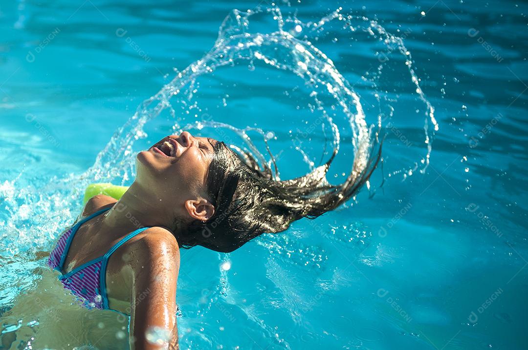 garotinha se divertindo em piscina com água azul