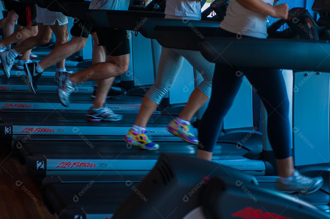 pessoas correndo em esteira  de academia