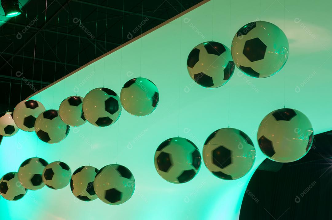 Bolas de futebol penduradas sobre luz verde