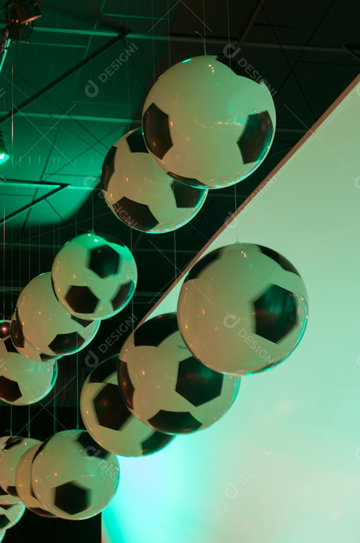 Bolas de futebol penduradas sobre luz verde