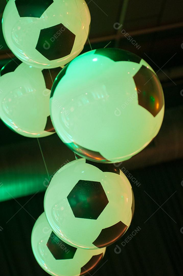 Bolas de futebol penduradas sobre luz verde