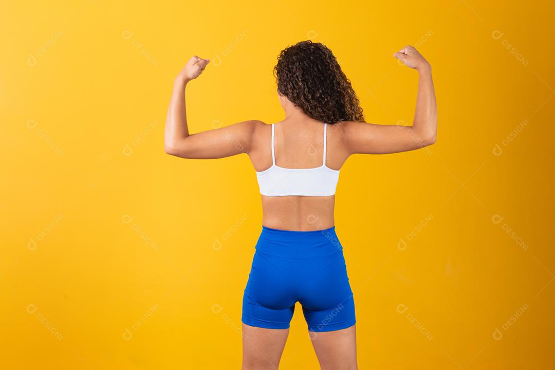 Atlética jovem mostrando os músculos das costas e bíceps