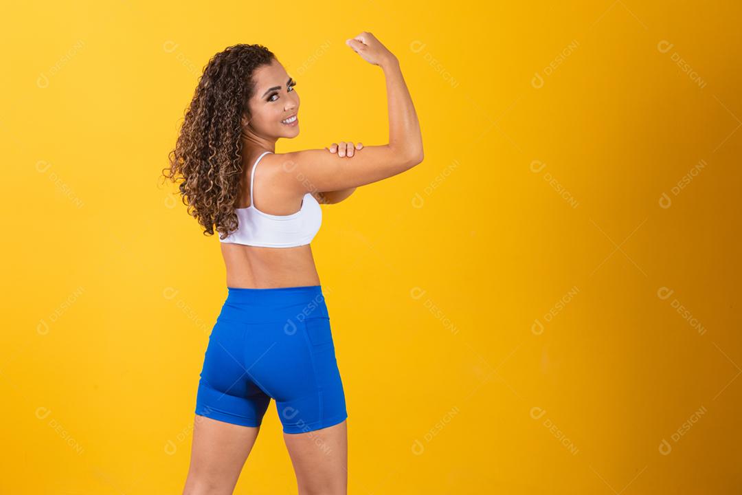 Atlética jovem mostrando os músculos das costas e bíceps