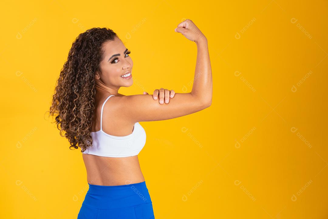 Atlética jovem mostrando os músculos das costas e bíceps