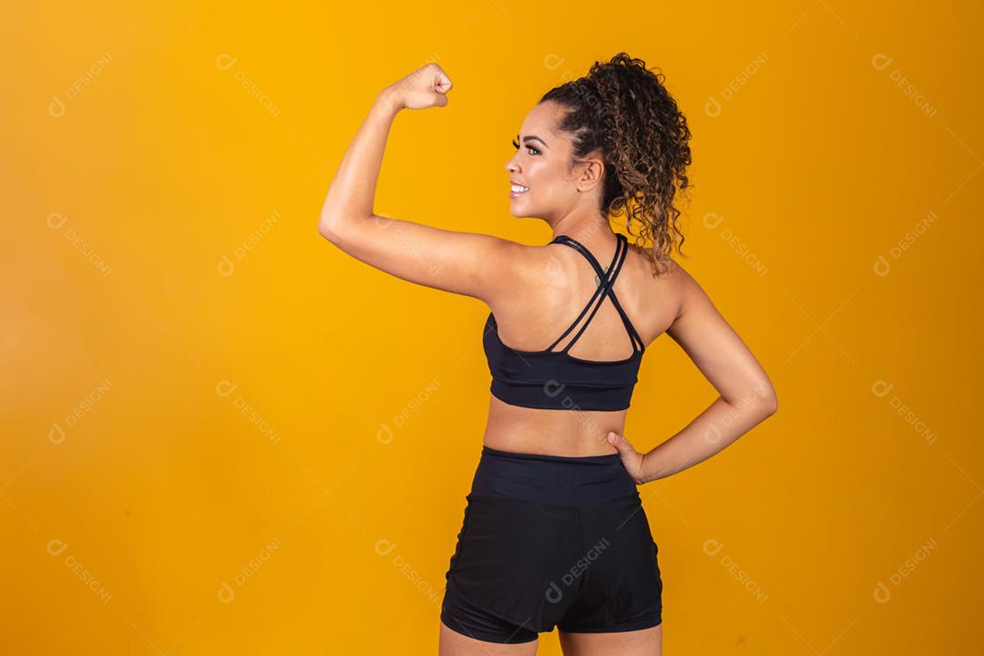 Atlética jovem mostrando os músculos das costas e bíceps