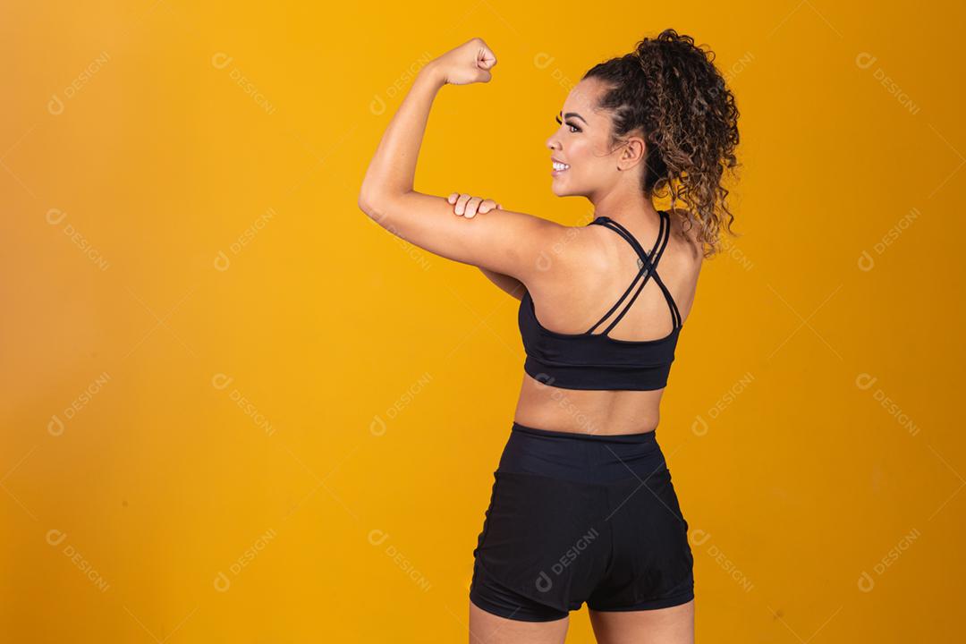 Atlética jovem mostrando os músculos das costas e bíceps