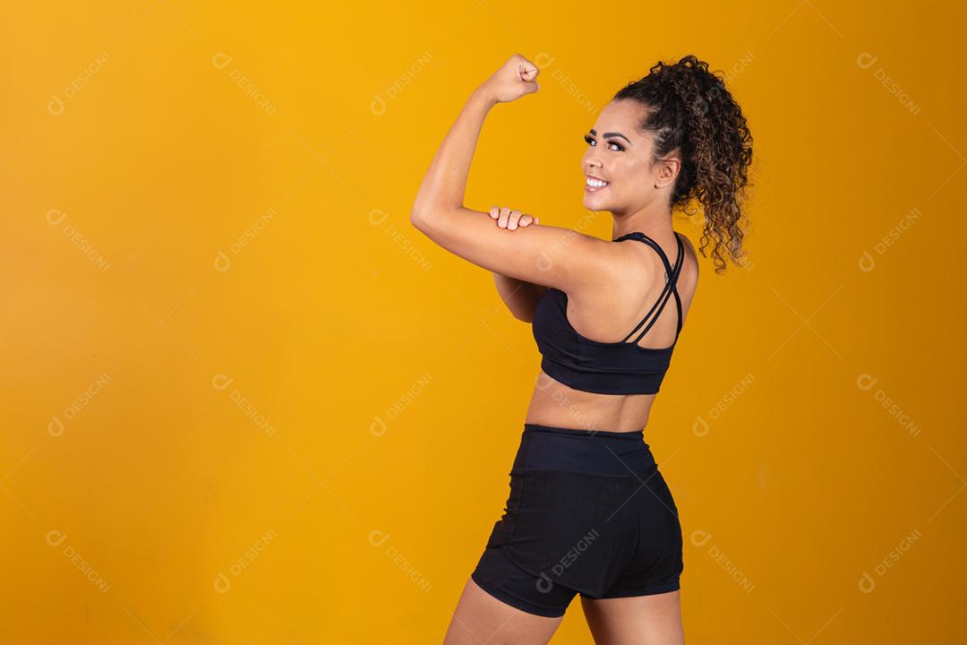 Atlética jovem mostrando os músculos das costas e bíceps