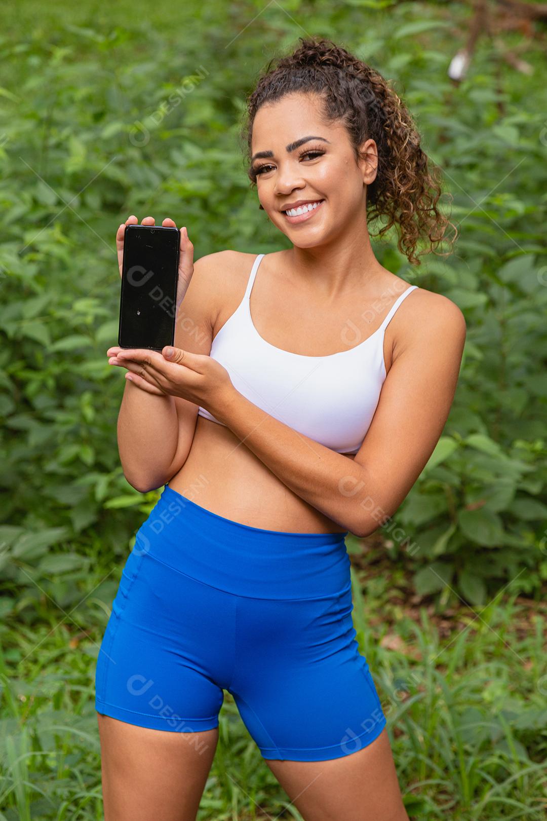 Uma Mulher sorrindo e mostrando o celular Imagem JPG