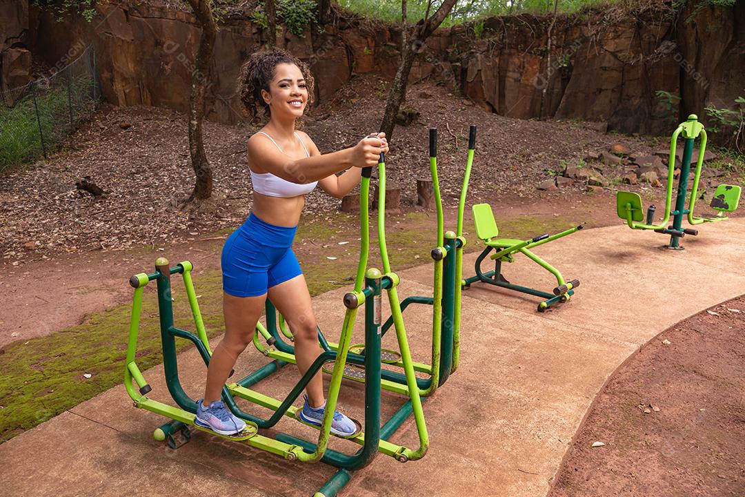 Jovem se exercitando ao ar livre em aparelhos públicos da cidade.