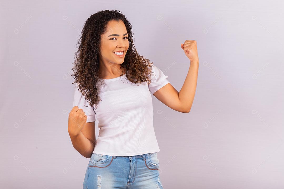jovem afro que ganha competição grita e comemora isolado no fundo branco.