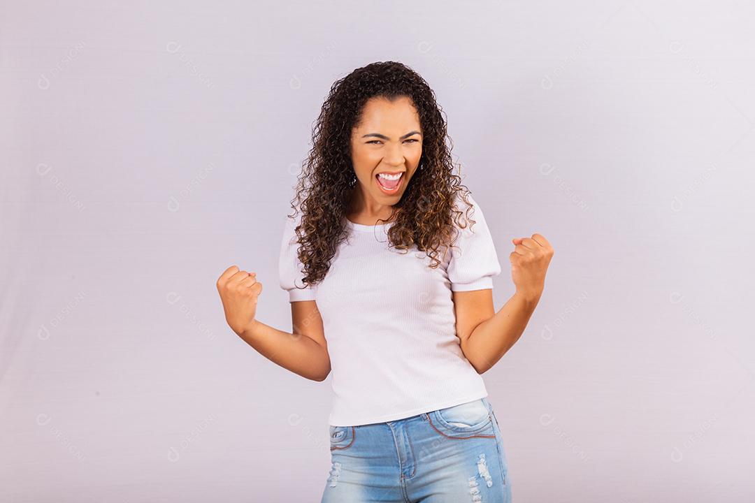 jovem afro que ganha competição grita e comemora isolado no fundo branco.