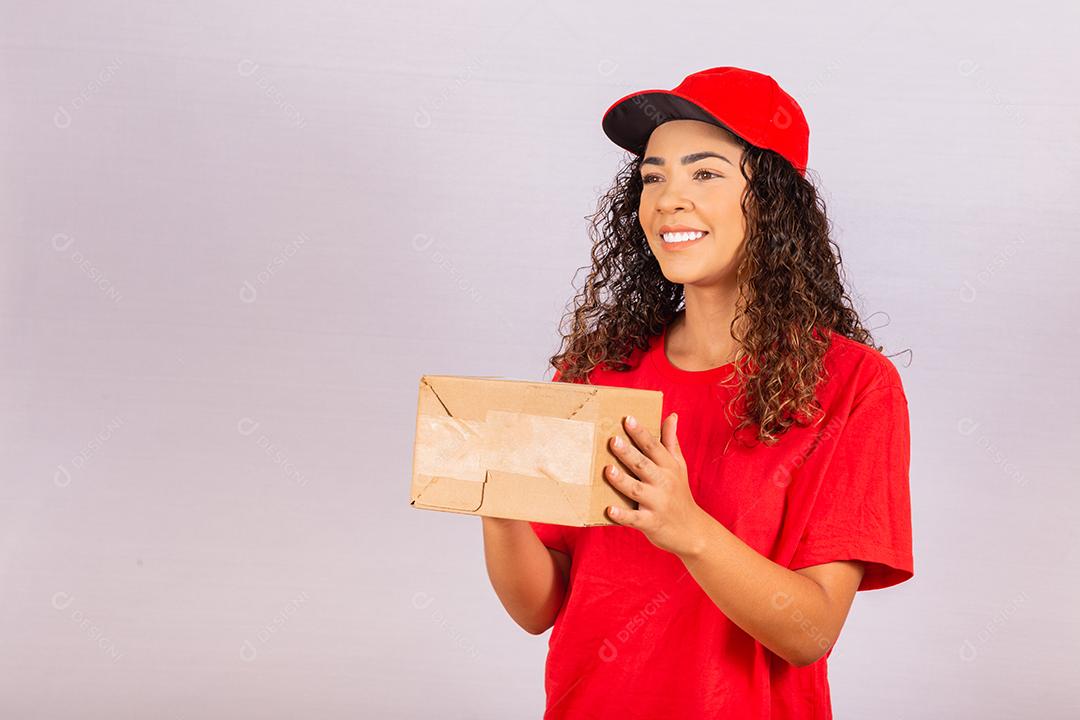 Linda jovem mensageiro entregando um pacote. Uma entregadora de uniforme vermelho está sorrindo