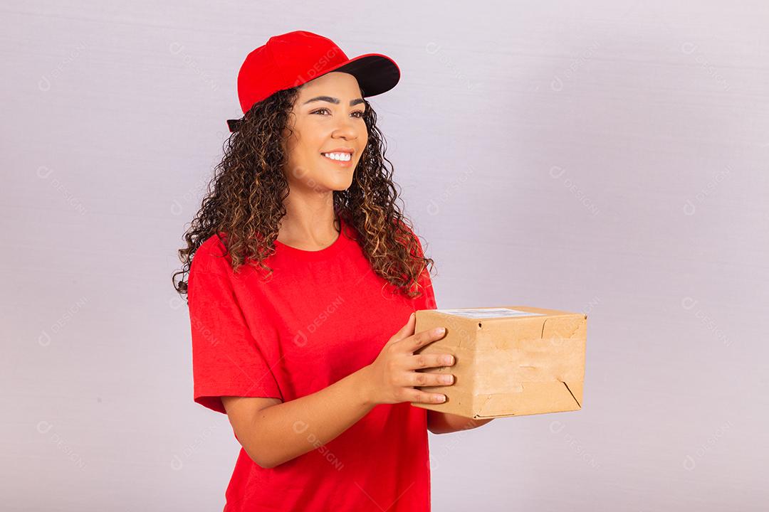 Beautiful young courier delivering a package. A delivery woman in a red uniform is smiling