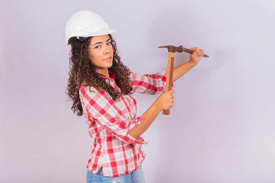 Mulher de empreiteiro segurando um martelo sobre fundo branco.