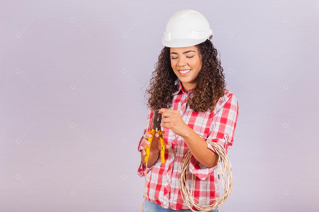 Técnica feminina. Mulher eletricista em fundo branco Eletricista de mulher segurando fio e alicate.