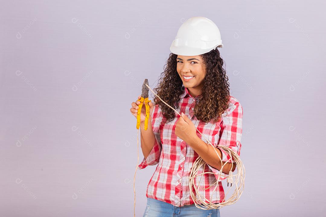 Técnica feminina. Mulher eletricista em fundo branco Eletricista de mulher segurando fio e alicate.