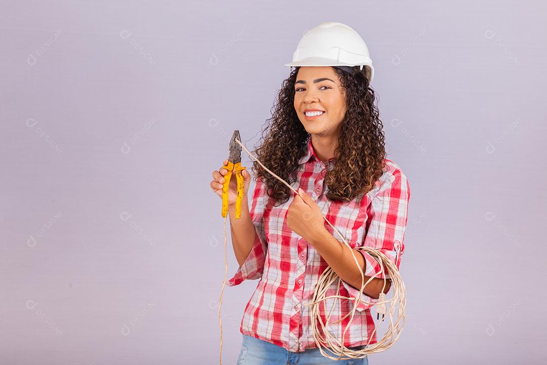Técnica feminina. Mulher eletricista em fundo branco Eletricista de mulher segurando fio e alicate.