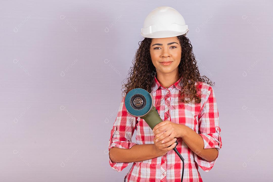 mulher afro segurando uma lixadeira elétrica. conceito de material de construção