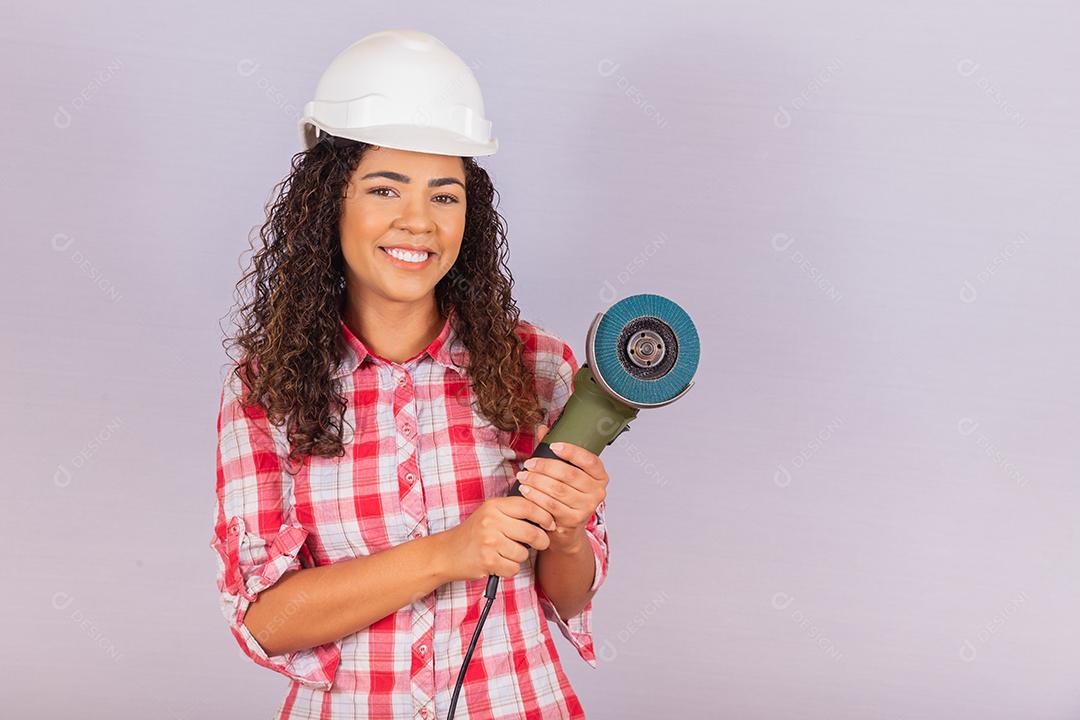 mulher afro segurando uma lixadeira elétrica. conceito de material de construção