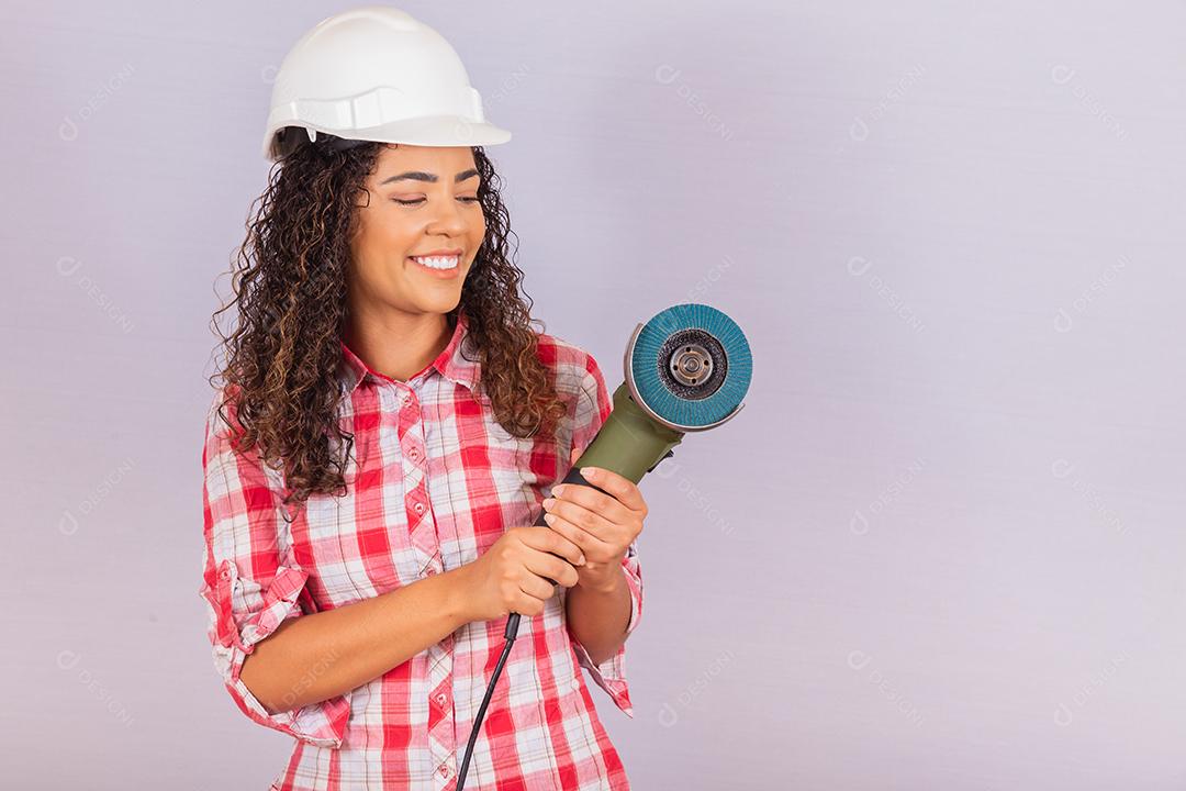 mulher afro segurando uma lixadeira elétrica. conceito de material de construção