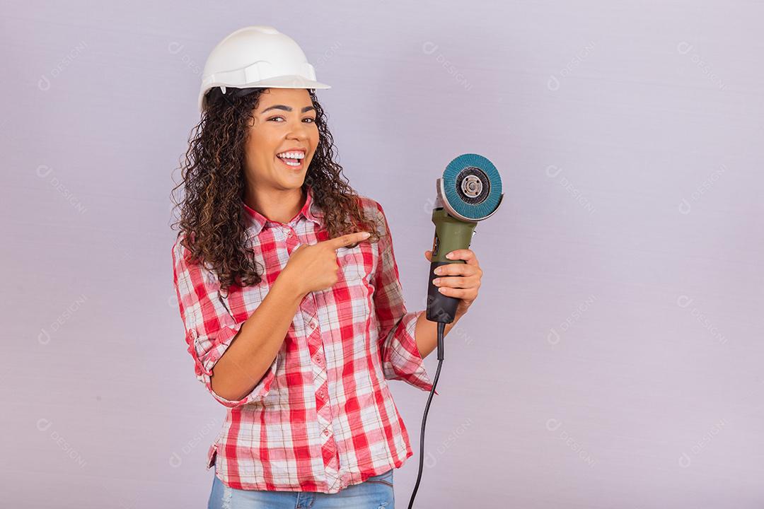 mulher afro segurando uma lixadeira elétrica. conceito de material de construção