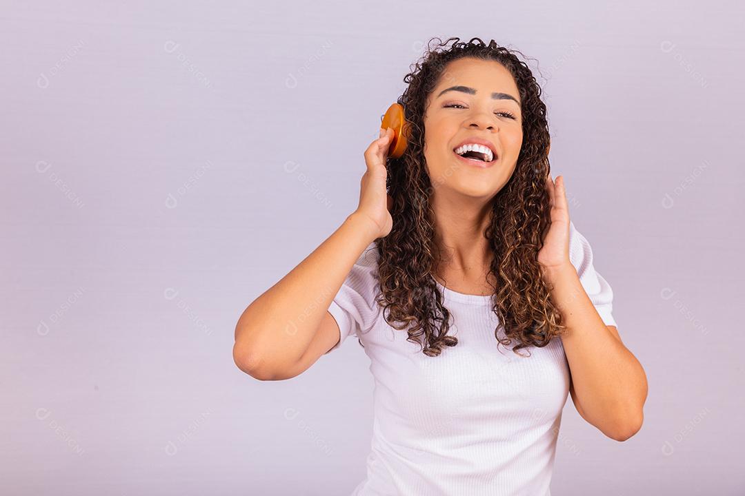 mulher afro com fones de ouvido, ouvindo música e dançando. Alegre jovem com fones de ouvido