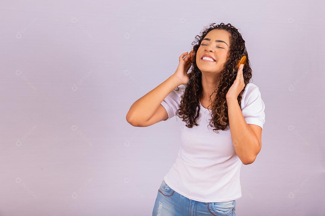 mulher afro com fones de ouvido, ouvindo música e dançando. Alegre jovem com fones de ouvido