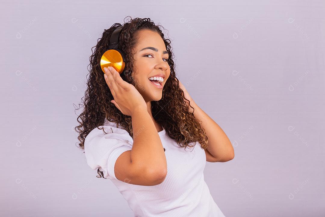 mulher afro com fones de ouvido, ouvindo música e dançando. Alegre jovem com fones de ouvido