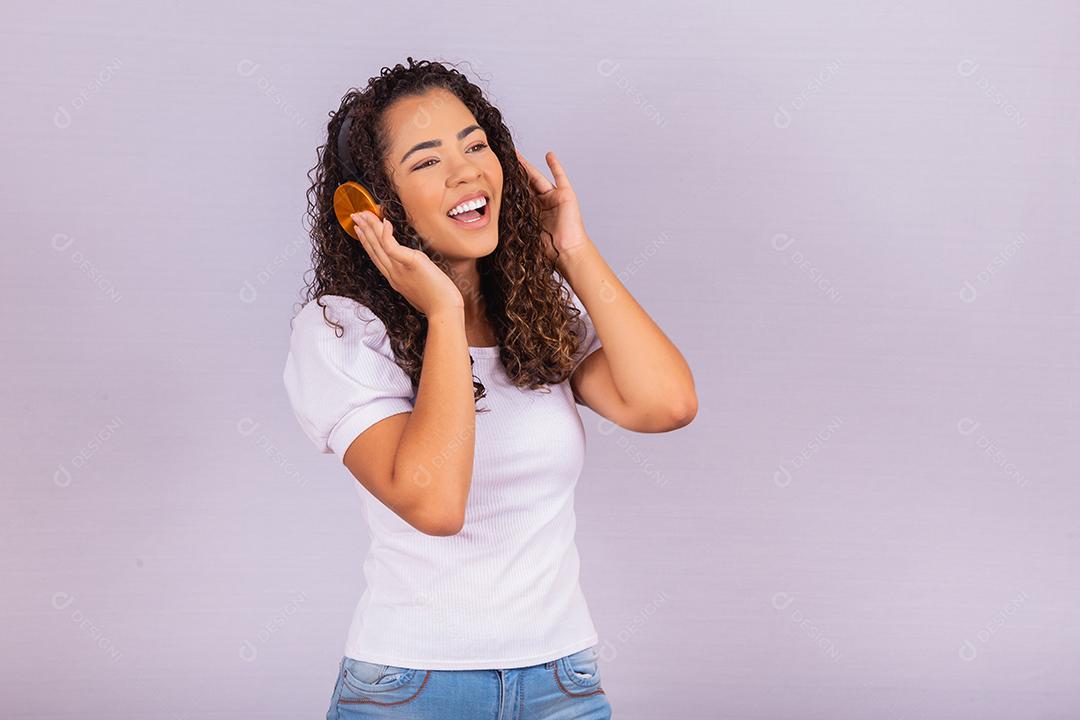 mulher afro com fones de ouvido, ouvindo música e dançando. Alegre jovem com fones de ouvido