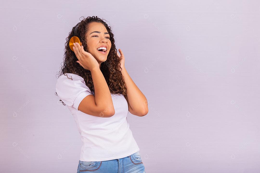 mulher afro com fones de ouvido, ouvindo música e dançando. Alegre jovem com fones de ouvido