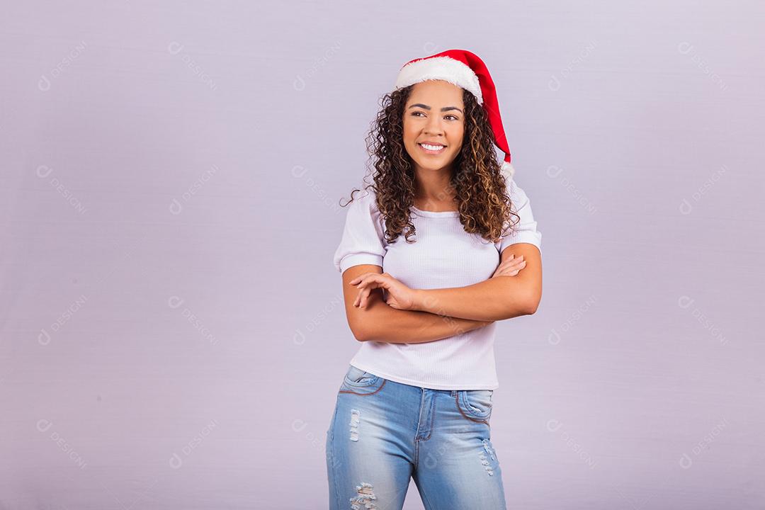 jovem afro com chapéu de papai noel para campanhas de natal em fundo branco com espaço livre para texto. Braços cruzados