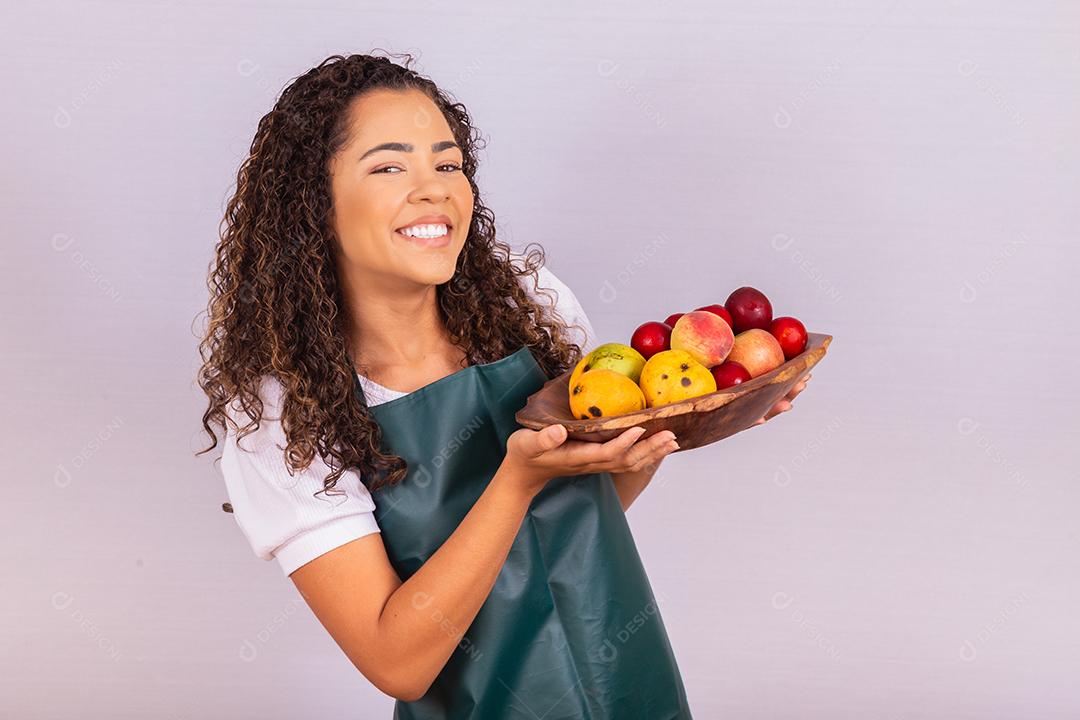 mulher jovem agricultor segurando uma tigela com frutas. Manga, pêssego e maçã na cesta na mão da menina