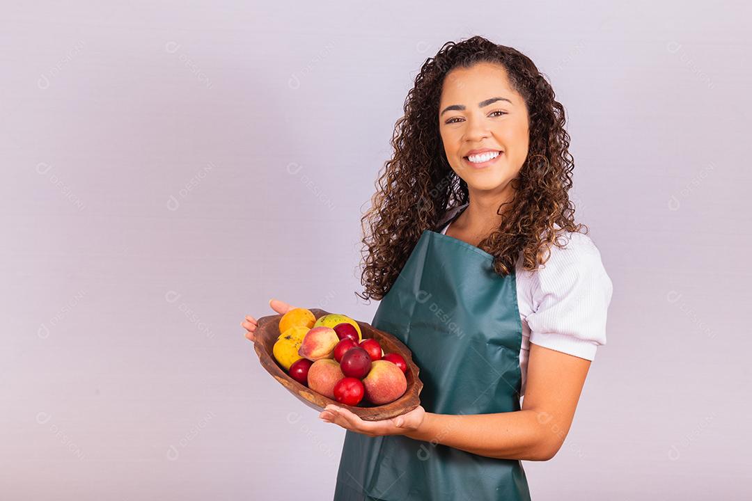 mulher jovem agricultor segurando uma tigela com frutas. Manga, pêssego e maçã na cesta na mão da menina